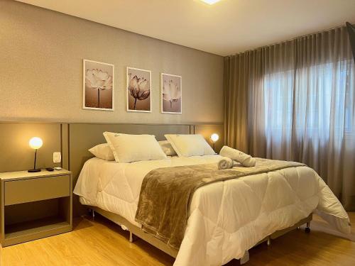 ein Schlafzimmer mit einem Bett mit drei Bildern an der Wand in der Unterkunft Apartamentos Solar da Garibaldi CENTRO by Achei Gramado in Gramado