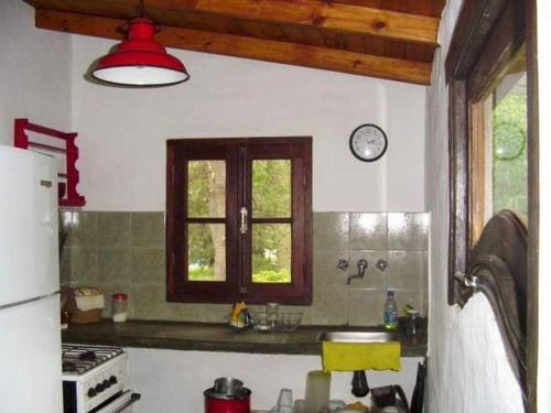 a kitchen with a sink and a clock on the wall at Cabaña Hannah in San Marcos Sierras