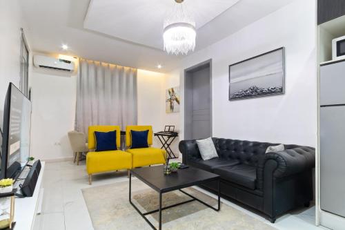 a living room with a black couch and yellow chairs at Exclusive Upscale 1 Bedroom Apartment in Lekki phase 1 in Lagos