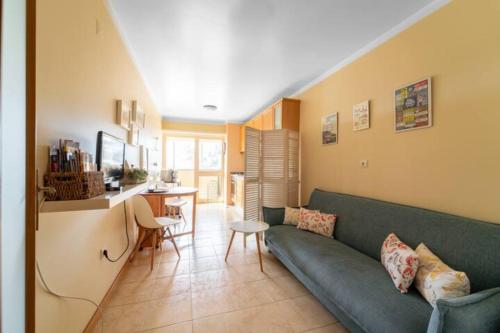 uma sala de estar com um sofá verde e uma cozinha em Apartamento da Praça no Porto