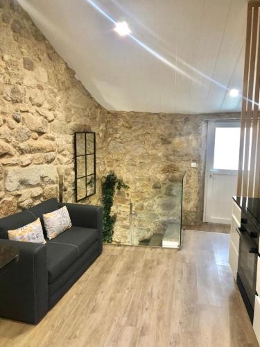 a living room with a couch and a stone wall at Casa Arrabal in Oia
