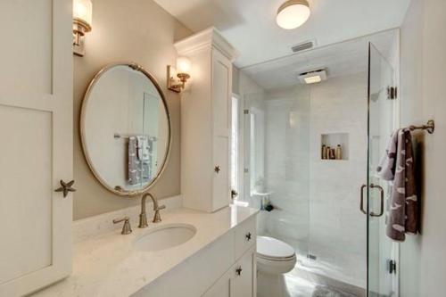 Baño blanco con lavabo y espejo en After Dune Delight - 626 Beachview Drive, en Saint Simons