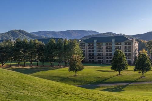 a building on a grassy hill with trees in front at RiverStone Resort & Spa in Pigeon Forge