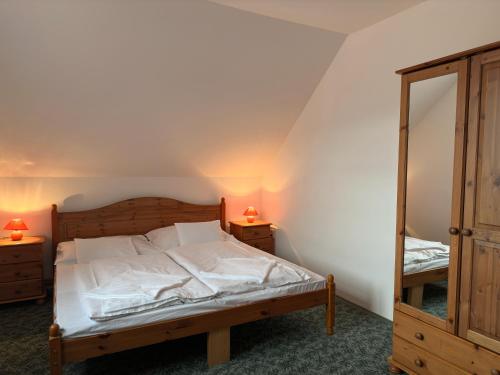 a bedroom with a bed with white sheets and a mirror at HAnd Birtok in Siklós