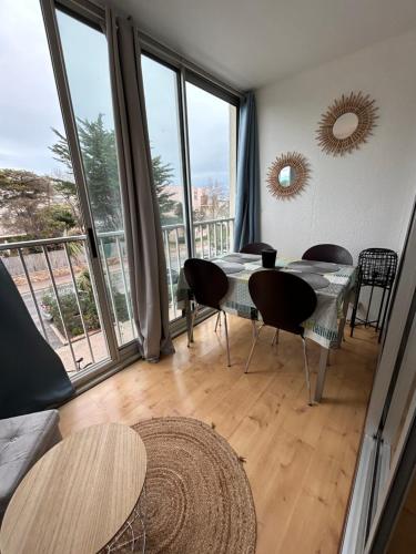 une salle à manger avec une table et des chaises et une grande fenêtre dans l'établissement Petit T2 proche de la plage, à Sète