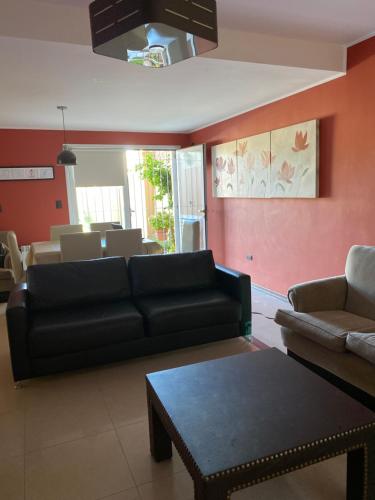 ein Wohnzimmer mit einem schwarzen Sofa und einem Tisch in der Unterkunft Vistalba House in Ciudad Lujan de Cuyo