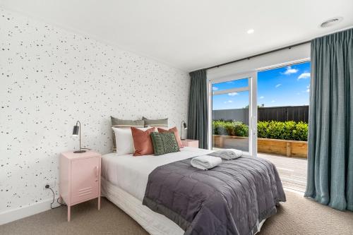 a bedroom with a bed and a large window at Lavish at the Lake in Taupo