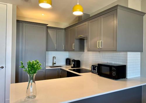a kitchen with gray cabinets and a vase of flowers on a counter at Margate Main Sands Sea views Central Location Sleeps 4 in Kent