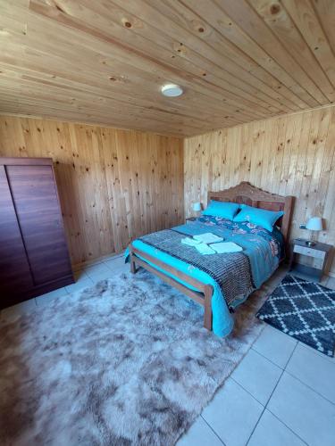 Cabaña Loft Curaco de Vélez في Curaco de Velez: غرفة نوم بسرير وسقف خشبي