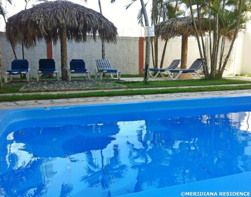 a swimming pool with blue chairs and palm trees at Residence Meridiana in Juan Dolio