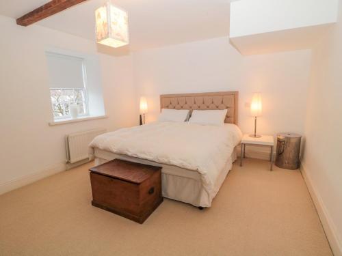 a bedroom with a large white bed with a wooden table at 2 The Reformed Church in Alnwick