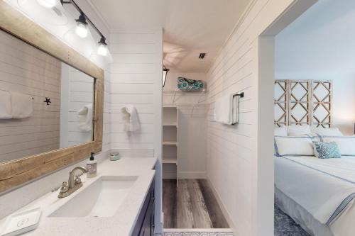 ein Badezimmer mit Waschbecken und Spiegel und einem Bett in der Unterkunft Harbour Oaks, Unit 214 in Demere Park