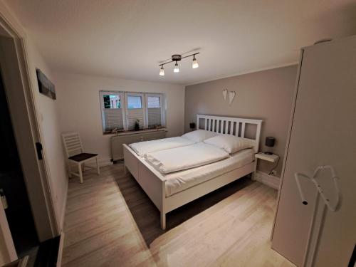 a bedroom with a white bed and a chair at Entspannung unter Reet in Bordelum