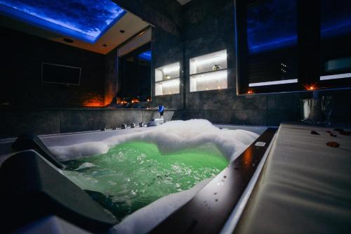a bathroom with a tub filled with green water at You & Me spa apartment in Zlatibor