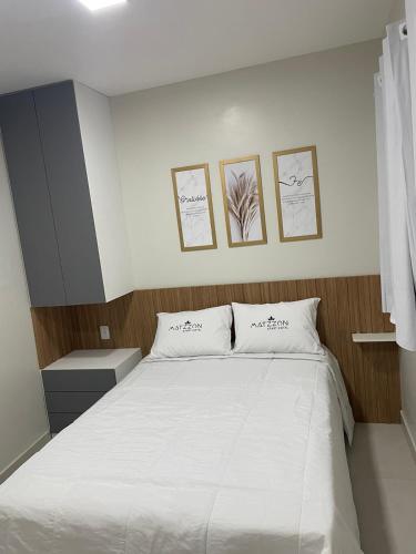a bedroom with a white bed with three pictures on the wall at Matzzon Apart Hotel in João Câmara