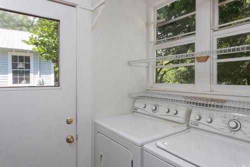 a white washing machine in a white kitchen with a window at Waterside - 829 Park Way in Saint Simons