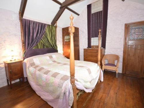 a bedroom with a canopy bed and a wooden floor at Granite Country Cottage west of Penzance in Sancreed