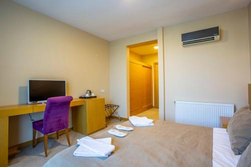 a hotel room with a desk and a purple chair at Olive Garden Hotel in İznik