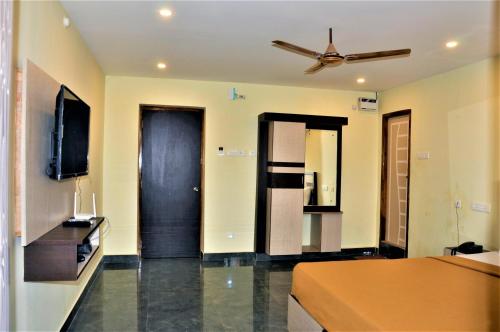 a living room with a bed and a ceiling fan at Srirathna Temple View Inn in Thanjāvūr