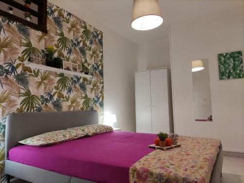 1 dormitorio con cama morada y pared en La Dimora Fiorita, en Catania