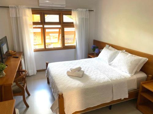 a bedroom with a bed with a towel on it at Pousada Villa Verde in Canela