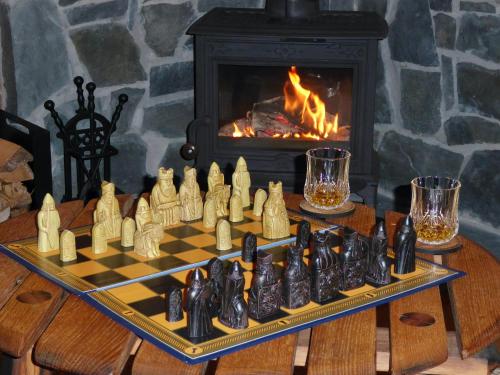 un tablero de ajedrez sobre una mesa frente a una chimenea en Cairnhill Lodge - Award-Winning Luxury Highland Retreat, en Blairgowrie