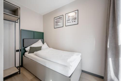 a small bedroom with a bed with white sheets at The Moss - Your unique hideaway in Obergurgl