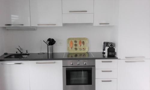 ブリッサーゴにあるBrissago: 3.5 Zi-Wohnung an extrem ruhiger Lage mit fantastischem Ausblickのキッチン(白いキャビネット、コンロ付)
