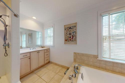 a bathroom with a tub and a sink and a mirror at 44 Dune House - 1901 Dixon Lane in Saint Simons Island