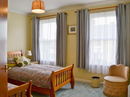 a bedroom with a bed and a chair and windows at Lyndhurst in Ely