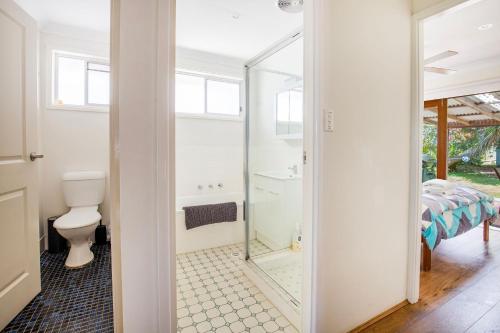 a bathroom with a toilet and a glass shower door at Sunbaker Pet Friendly Awards Finalist 4 Mins Walk to Culburra Beach in Culburra Beach