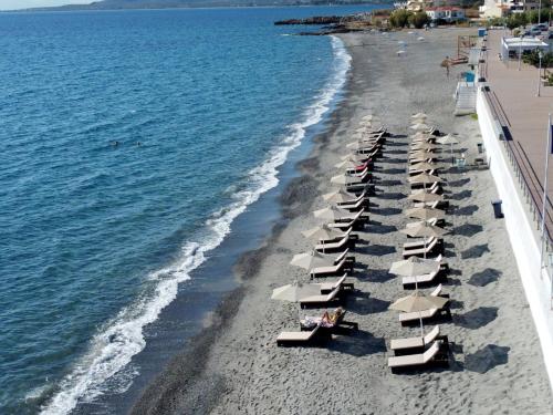 a beach with chairs and umbrellas and the ocean at Limira Mare Hotel in Neapolis