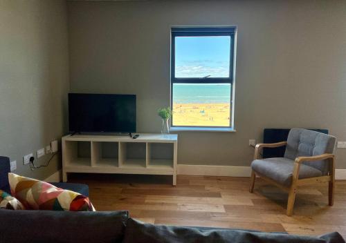 een woonkamer met een bank, een tv en een raam bij Margate Seaside Penthouse With Sea views Sleeps 6 in Kent