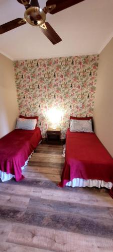 a room with two beds and a ceiling fan at Casa 24 Puerto Iguazu in Puerto Iguazú