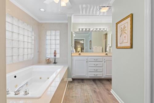ein weißes Badezimmer mit einer Badewanne und einem großen Spiegel in der Unterkunft Byrd's Nest - 1107 Beachview Drive in Demere Park