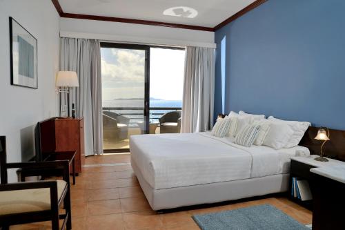 Habitación de hotel con cama, escritorio y ventana en Limira Mare Hotel en Neápolis