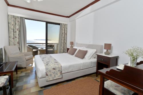 a white bedroom with a bed and a balcony at Limira Mare Hotel in Neapolis