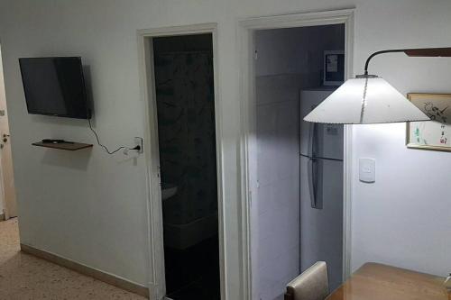 Habitación con puerta, TV y nevera. en departamento en Mar del Plata en Mar del Plata