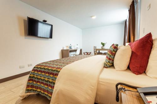 a hotel room with a bed with a tv on the wall at Hotel Carretero in Manizales