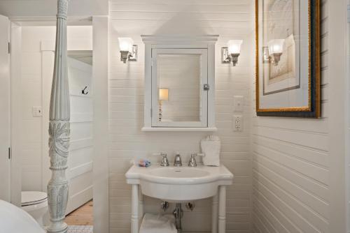 a white bathroom with a sink and a mirror at Endless Summer - 4217 - 6th Street in Saint Simons Island