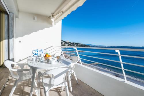 Biały stół i krzesła na balkonie z widokiem na ocean w obiekcie PANORAMIC SEA VIEW Apartment in the Mourré Rouge area of Cannes w Cannes