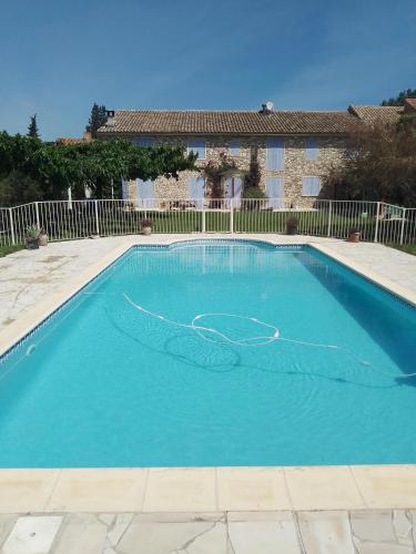 une piscine avec de l'eau bleue devant une maison dans l'établissement Mas des Rompides, à Maillane