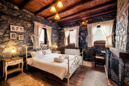 a bedroom with a bed and a stone wall at Ξενώνας Φωταξία in Palaios Agios Athanasios