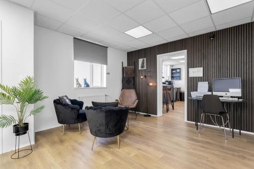 a living room with chairs and a desk and a television at Bank Guesthouse by KEF Airport in Keflavík