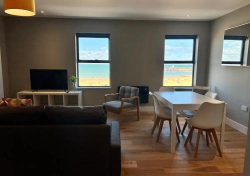 a living room with a table and chairs and windows at Beachfront Bliss Margate With Sea Views Sleeps 7 in Kent