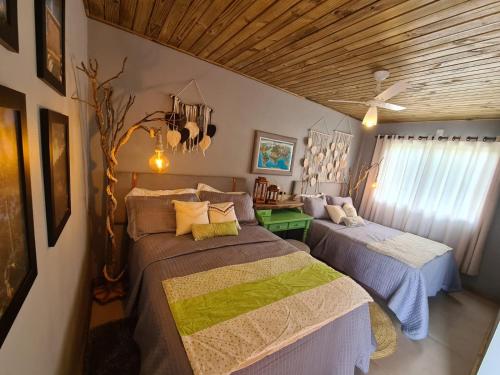 two beds in a room with wooden ceilings at Refúgio dos Coiotes in Cambara do Sul