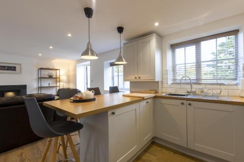 a kitchen with white cabinets and a wooden counter top at Stable Cottage in Whitby