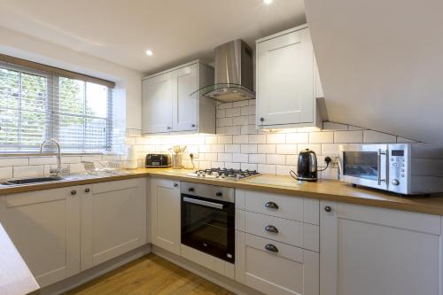 uma cozinha com armários brancos e um micro-ondas em Stable Cottage em Whitby