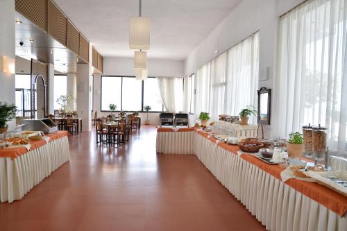 Habitación grande con mesas, sillas y ventanas. en Limira Mare Hotel, en Neápolis