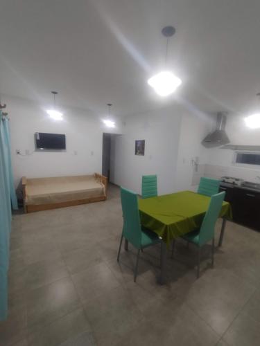 Habitación con mesa verde, sillas y cama en Departamentos Mora en General Alvear